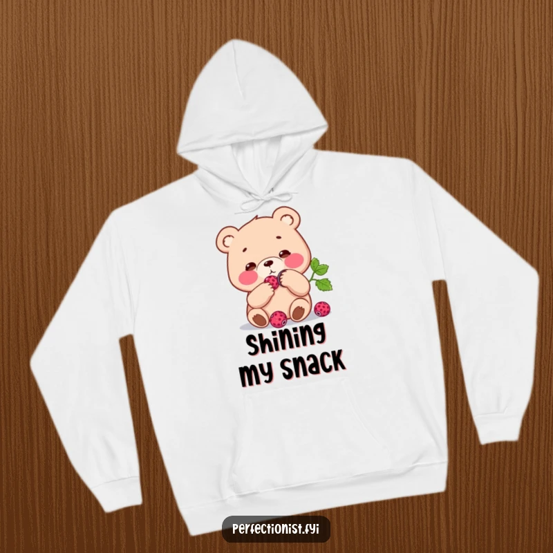 Funny Hoodie: Focused bear character polishing a single berry to a shine, bringing cozy humor and a sense of meticulous care.