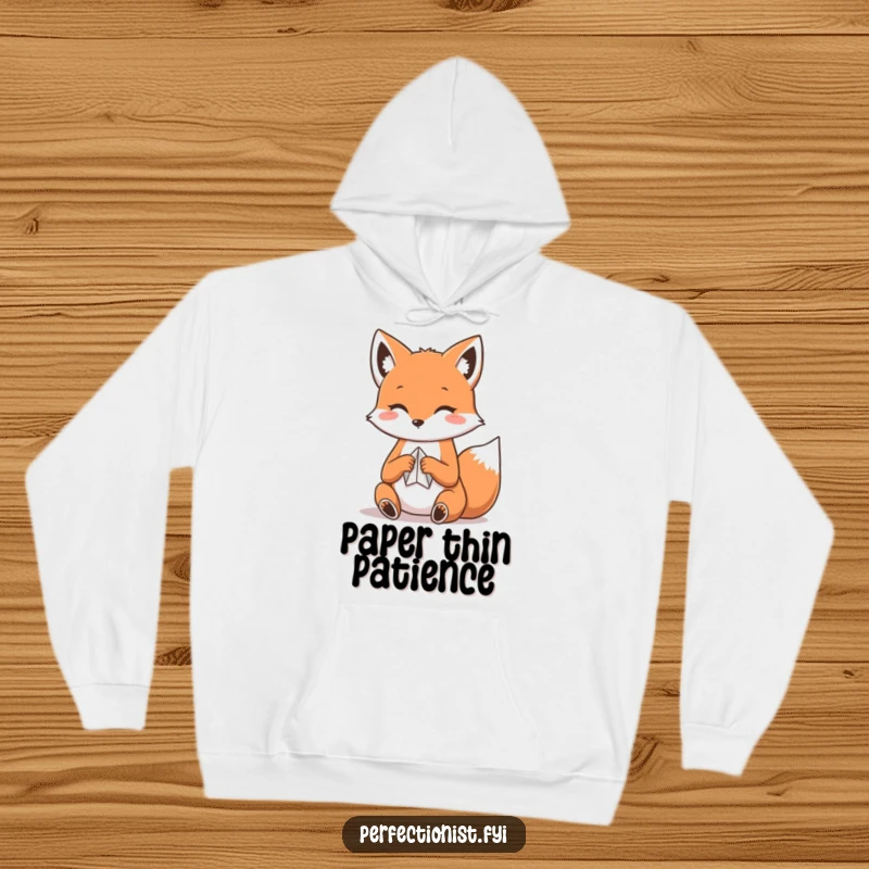 Funny Kawaii fox hoodie, a cute fox concentrating on folding a small piece of paper, suggesting delicate craftsmanship.